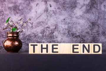 Word THE END made with wood building blocks on a gray background