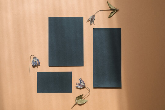 Overhead view of blank black stationery on a wooden table with flowers