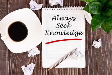 Always seek knowledge, an inscription in a notebook on a wooden table with a pen and a cup of...