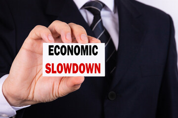 Obraz premium A businessman is holding a tablet with the text Economic Slowdown in front of him in his hands. Business concept.