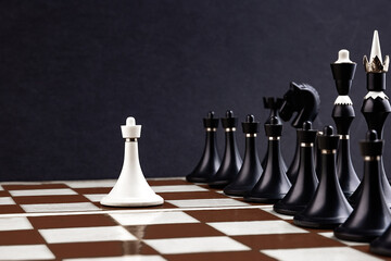White and black chess pieces on a chessboard on a dark background. Business concept. Game,...