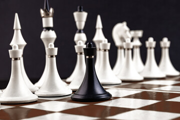 White and black chess pieces on a chessboard on a dark background. Business concept. Game,...