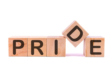 Word PRIDE is made of wooden building blocks lying on the table and on a light background. Concept.