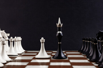 White and black chess pieces on a chessboard on a dark background. Business concept. Game,...