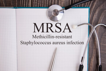 Notebook page with text MRSA Methicillin-resistant Staphylococcus aureus infection, on a table with...