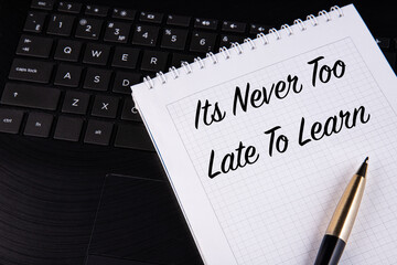 It's Never Too Late To Learn - written on a notebook with a pen.