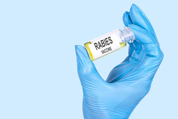 RABIES VACCINE text is written on a vial whose ampoule is held by a hand in a medical disposable...