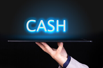 Man hand holds a tablet over which a neon text is written, the word CASH. Business concept.
