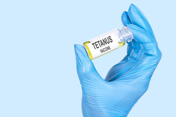 TETANUS VACCINE text is written on a vial whose ampoule is held by a hand in a medical disposable...