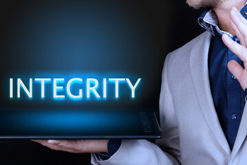 Businessman, man holds in his hand a tablet with a neon word, INTEGRITY text. Business concept.