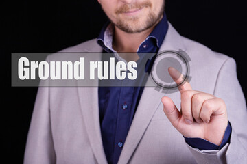 Businessman presses a button with the text GROUND RULES. Business concept.