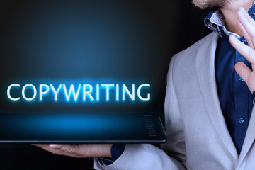 Businessman, man holds in his hand a tablet with a neon word, COPYWRITING text. Business concept.