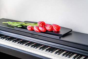 a bouquet of red scarlet tulips with delicate petals lie on the piano, a beautiful composition