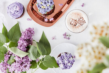 Floral feminine background. Purple cupcakes using trend Dreamy Escapism. Desserts on the golden...