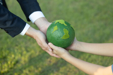 Businessman hand giving Earth globe to little boy as Earth day concept as corporate social...