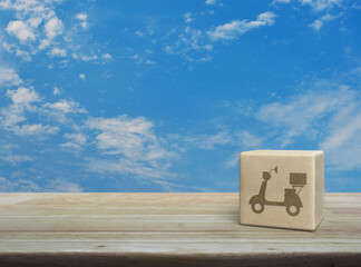 Motorcycle icon on wood block cube on wooden table over blue sky with white clouds, Business delivery service concept