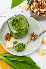 Pesto sauce made from wild garlic, walnuts, parmesan cheese and olive oil in a jar on a wooden...