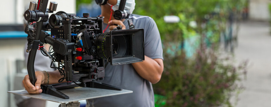 Movie shooting or video production and film crew team with camera equipment. Video camera operator working with equipment. Director of photography with a camera in his hands on the set