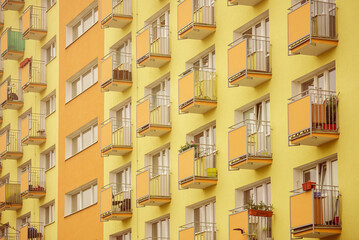 Żółto-pomarańczowa elewacja bloku mieszkalnego z wieloma balkonami. Styl lat siedemdziesiątych.  - obrazy, fototapety, plakaty