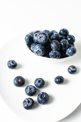 Fresh blueberries in a white bowl on a white background, with room for text