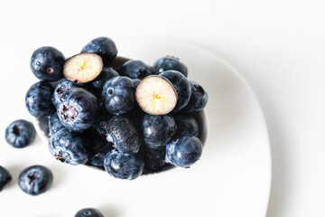 Fresh blueberries in a white bowl on a white background, with room for text