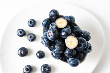 Fresh blueberries in a white bowl on a white background, with room for text