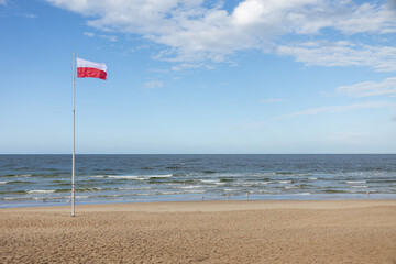 Polskie barwy narodowe, Polska flaga  na tle nieba nad morzem. Bałtyk Kołobrzeg Zachodniopomorskie  - obrazy, fototapety, plakaty