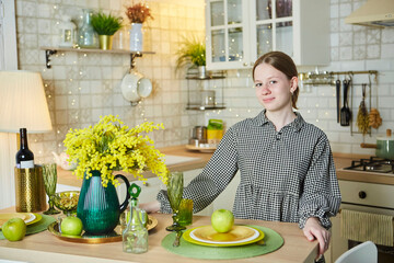 Portrait of a beautiful young girl in the kitchen. Spring flowers in the interior - 788033412