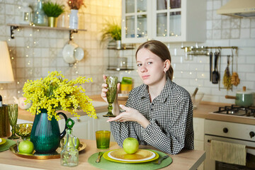 Portrait of a beautiful young girl in the kitchen. Spring flowers in the interior - 788033417