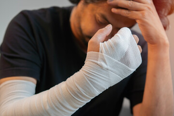 Middle aged man wearing a black shirt injured his hand feel stressed and worried.
