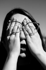 Conceptual portrait of a woman in eyeglasses. Young attractive woman covering her face with a her...