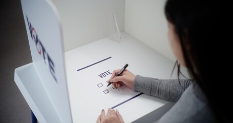 Asian female voter comes to voting booth at polling station, makes choice and votes for Republican...