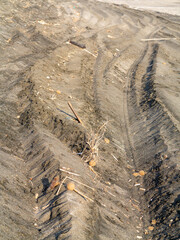 Macrofotografia in primo piano di spiaggia solitaria, con orme di pneumatici, legnetti solitari. 
