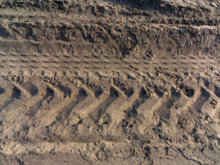 Macrofotografia in primo piano di spiaggia solitaria, con orme di pneumatici, legnetti solitari. 