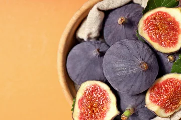  Fresh ripe figs in a wooden bowl on an orange background © Atlas