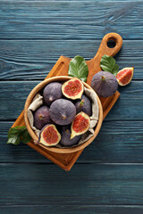 Fresh ripe figs in a wooden bowl on a blue background