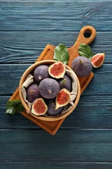  Fresh ripe figs in a wooden bowl on a blue background © Atlas