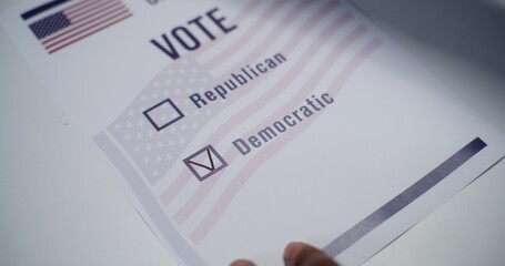 Close up of anonymous US citizen placing paper ballot on the table in voting booth. Voting for...