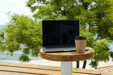 Laptop on table with coffee overlooking the sea