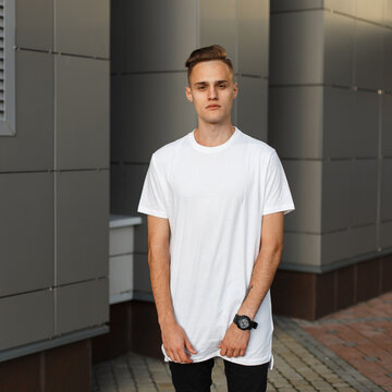 Handsome man model with hairstyle in fashionable white mock-up T-shirt in the city