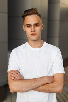 stylish handsome man with a hairstyle in a fashion white mock-up T-shirt stands hand in hand in the city