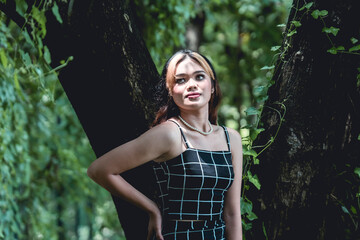 Young woman in goth-inspired outfit posing in a serene forest backdrop