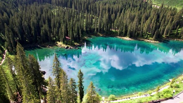 Idyllic nature scenery- trasparent mountain lake Carezza surrounded by Dolomites rocks- one of the most beautiful lakes of Alps. South Tyrol region. Italy, aerial drone video
