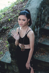 Mysterious young woman in goth-inspired attire posing in a lush forest