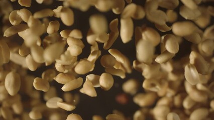 Top view of crispy roasted salted peanuts falling in super slow motion close up. Hot delicious fried peanuts snacks with smoke flying. High speed 1000 fps vertical video - Powered by Adobe