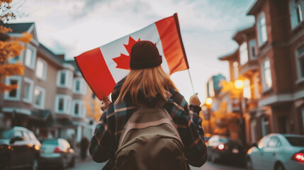 Fototapeta premium Young woman holding a canadian flag in her hands on the background of the city