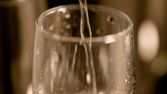 キラキラとフルートグラスに注がれるシャンパン・スパークリングワイン・炭酸の水と立ち上る泡バブルのマクロ撮影 スローモーション　パーティー・ウエディング・誕生日・クリスマス・記念日のイメージ