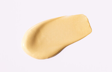 creamy cosmetic texture of golden shining color cosmetic smear on a light background