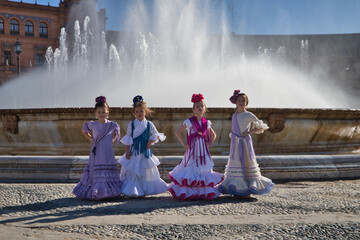 Four girls dancing flamenco, posing looking at camera, wearing typical flamenco costumes next to a...