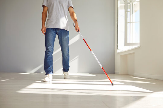 Midsection portrait of a blind man at home, utilizing a walking stick for enhanced mobility. This image reflects the pursuit of accessibility and highlights the importance of health and independence.